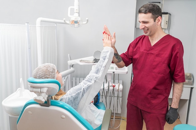 Dental clinic patient, sitting in a chair, claps a doctor hand