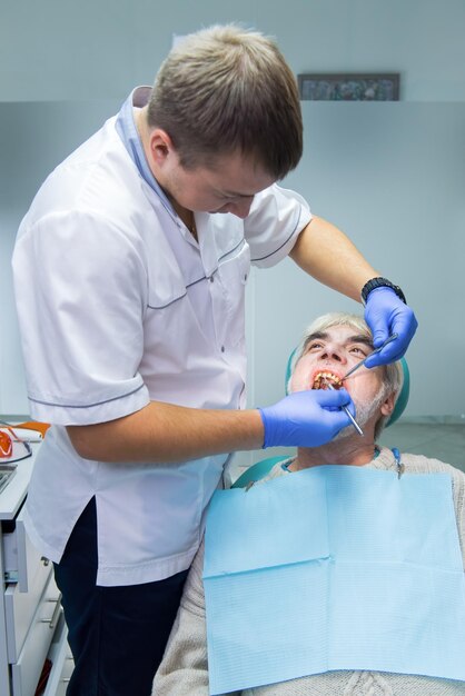 Dental doctor with elderly patient senior male at dentist office