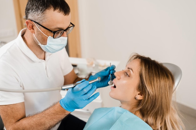 Стоматологическая дрель Стоматолог сверлит зубы женщины в стоматологической клинике Зубная пломба для девочки-пациента
