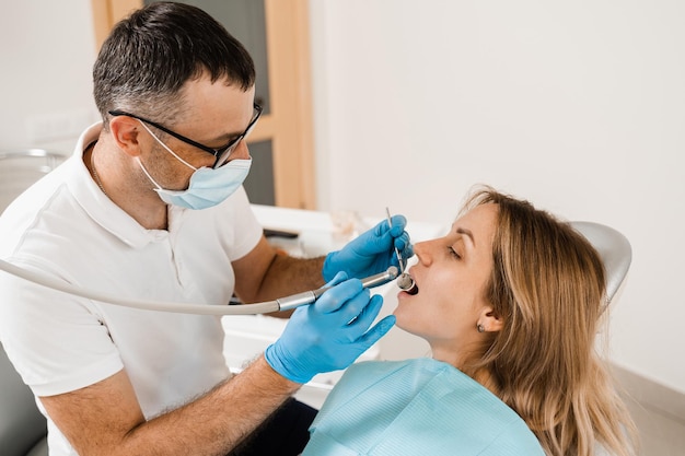 Стоматологическая дрель Стоматолог сверлит зубы женщины в стоматологической клинике Зубная пломба для девочки-пациента