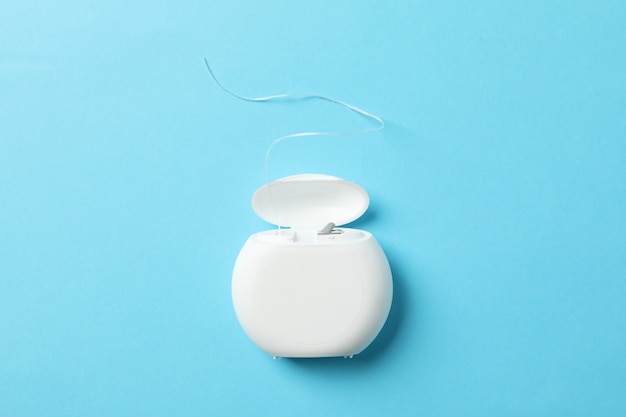 Dental floss on blue background, space for text