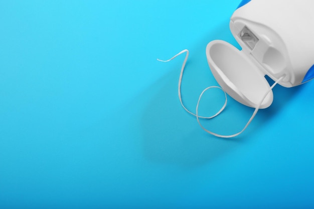 Dental floss on color background