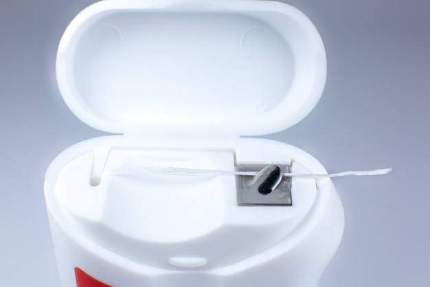 Dental floss on a gray background. Opened box, close up photo.