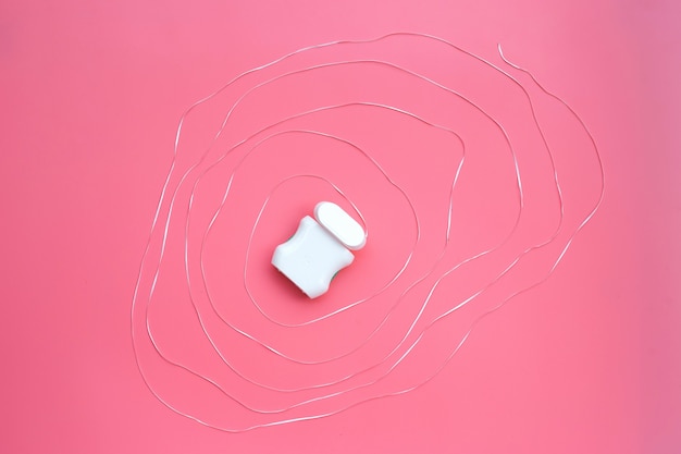 Dental floss on pink background.