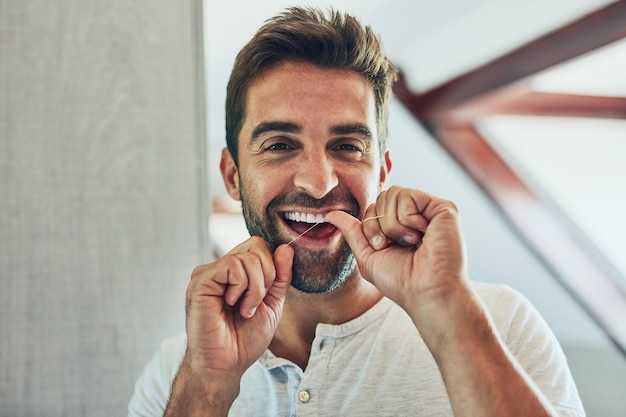 Ritratto del filo interdentale e denti con l'uomo nello specchio del bagno per la pulizia della routine mattutina e dell'igiene orale