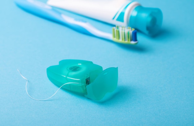 Dental floss and toothbrush on a blue background