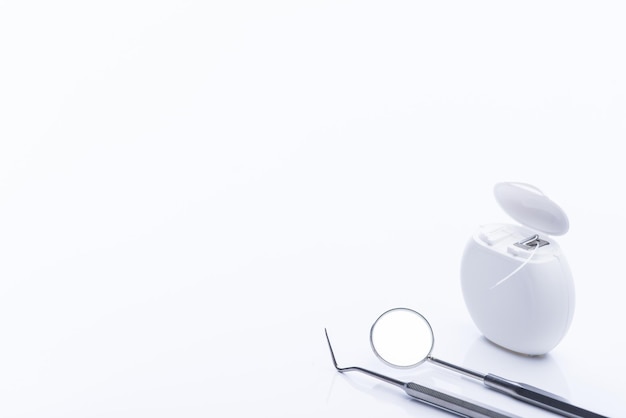 Dental floss with basic dental tools on a white table