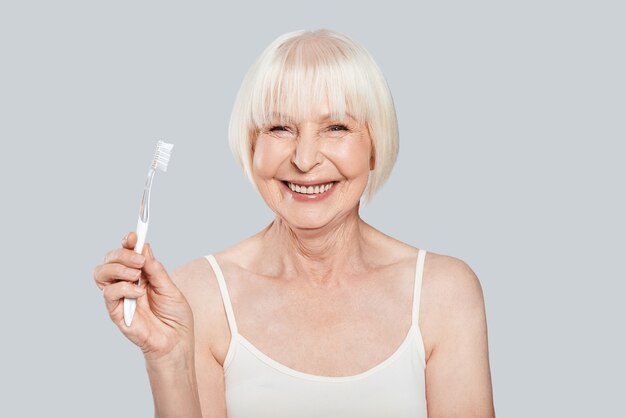 Dental health. Beautiful senior woman holding toothbrush and smiling 