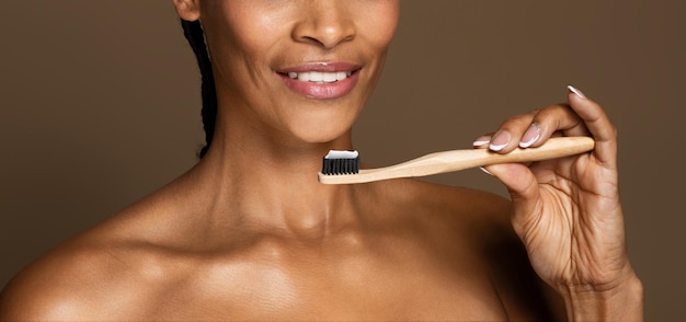 Dental health smiling black middle aged woman holding toothbrush with toothpaste panorama cropped