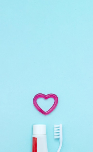 Photo dental hygiene and health conceptual image closeup of a toothpaste toothbrush and toothpaste heart on blurred blue background