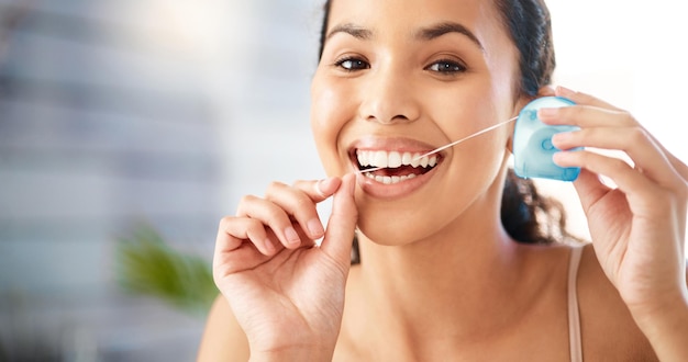 Фото Гигиена зубов является приоритетом снимок молодой женщины, чистящей зубы зубной нитью дома