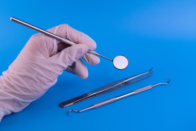 Dental instrument in the hand of the doctor on a blue background