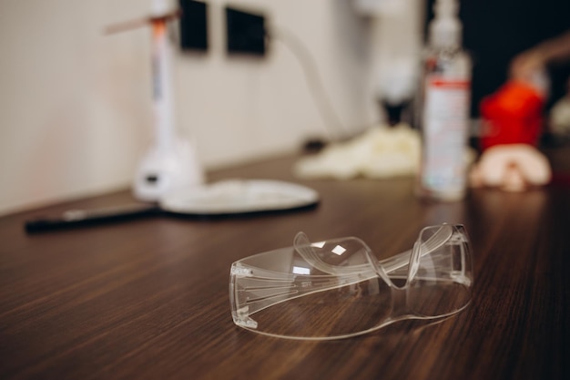 Стоматологические медицинские очки с бинокулярными линзами в стоматологической клинике Стоматологические очки или стоматологическая оптика в настоящей медицинской лаборатории Современное технологическое оборудование на заднем плане операционной