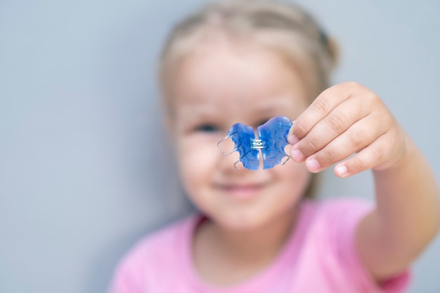 Dental plate. Expansion of the jaw in a child. A plate to heaven. There is not enough room for the molars. Happy girl holding an orthodontic plate in her hands