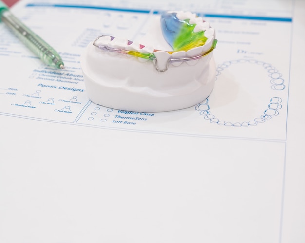 Photo dental retainer orthodontic appliance on the colour background.