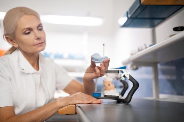 Dental technician examining the cast model of teeth she did