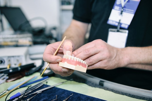 Dental technician manifacturing medical tooth prosthetic in laboratory