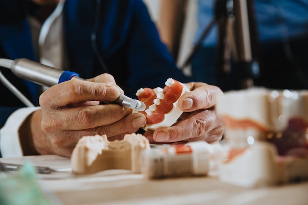 A dental technician processes a cast from the jaw of the patient