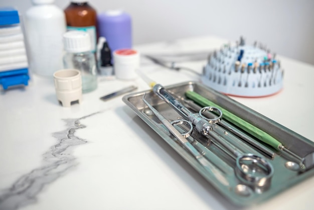 Dental tweezers lie in a metal tray and a bunch of other parts