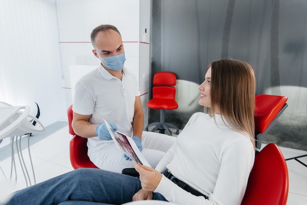 The dentist advises a young beautiful woman about the treatment and prosthetics of teeth in modern white stomatolgia Dental prosthetics treatment and teeth whitening