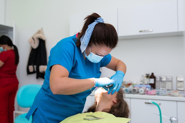 Dentist appointment at a dental clinic placing braces locks on the teeth and pulling the archwire to fix it