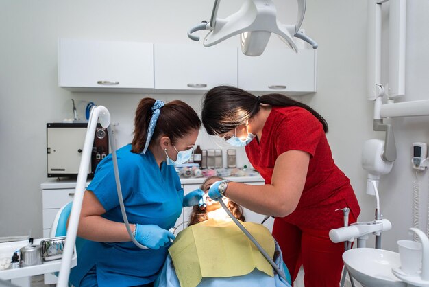 Dentist appointment at a dental clinic placing braces locks on the teeth and pulling the archwire to