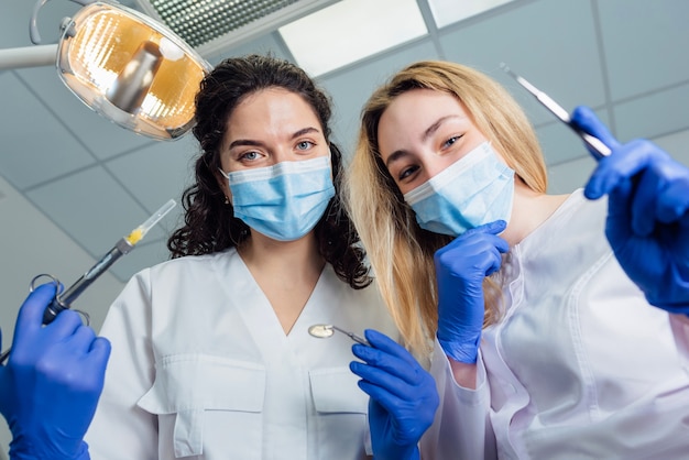 Foto dentista e assistente si chinarono sul paziente che teneva in mano lo strumento