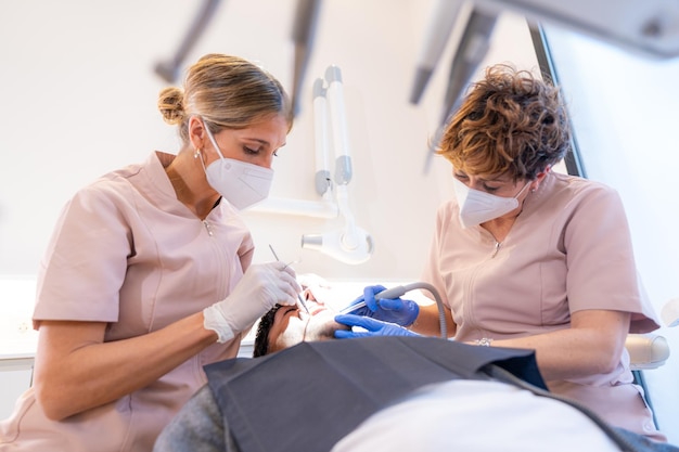 Dentist and assistant performing a mouth and tooth filling on a young client in the modern dental clinic