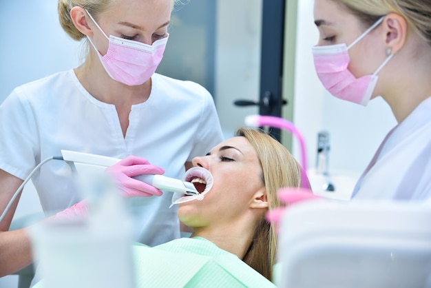 Dentist and assistant scaning patient's teeth with intraoral 3d scanner