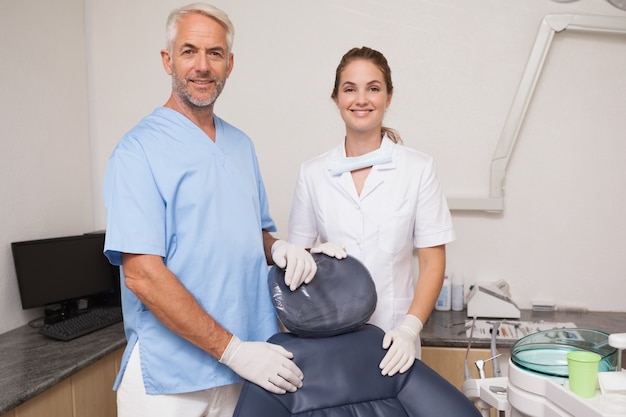 Dentist and assistant smiling at camera inviting you to the chair