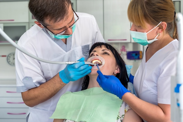 The dentist and assistant treat the patient with dental drill