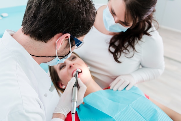 Dentist and assistant treating woman in clinic