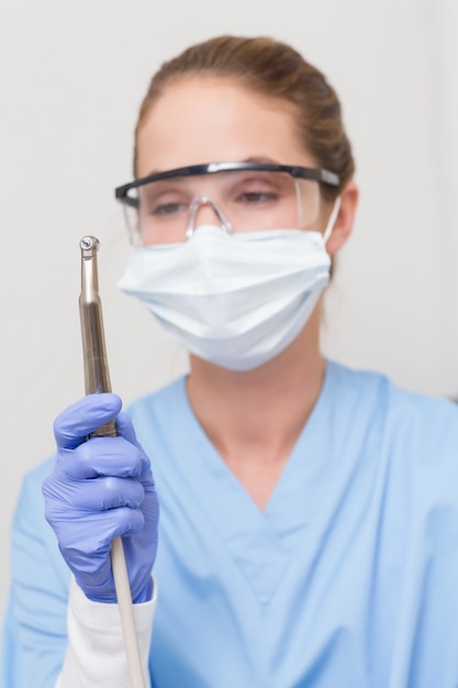 Dentist in blue scrubs holding dental drill