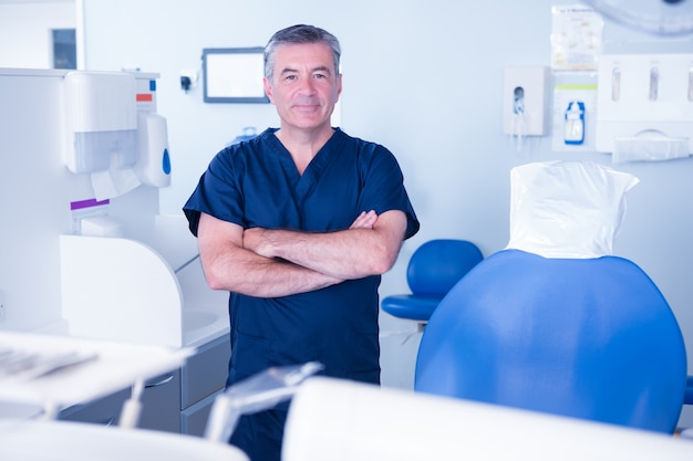 Dentist in blue scrubs smiling at camera