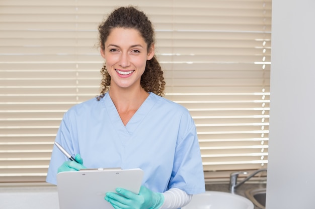 Dentist in blue scrubs writing on clipboard