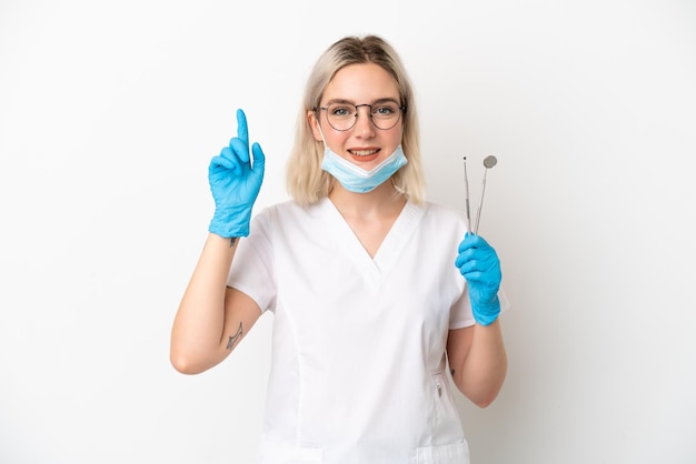 Фото Кавказская женщина стоматолога держит инструменты, изолированные на белом фоне, указывая вверх прекрасную идею