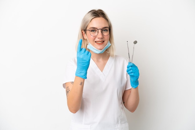 Foto dentista donna caucasica che tiene strumenti isolati su sfondo bianco facendo il gesto in arrivo