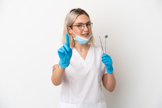 白い背景で隔離のツールを保持している歯科医の白人女性が指を示して持ち上げる