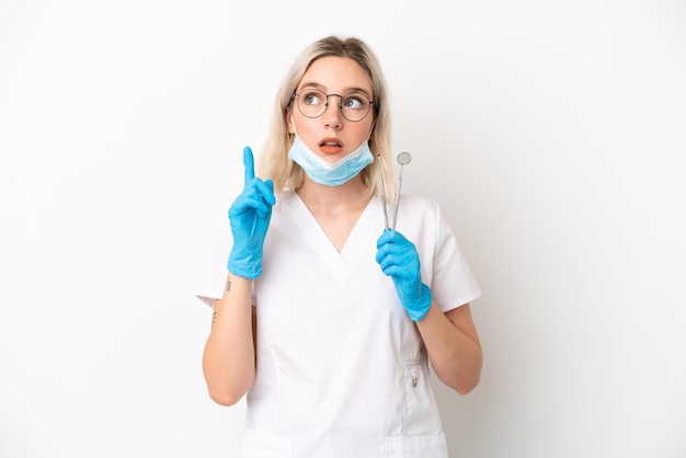 Dentist caucasian woman holding tools isolated on white background thinking an idea pointing the finger up