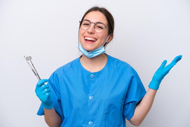 Dentist caucasian woman holding tools isolated on white background with shocked facial expression