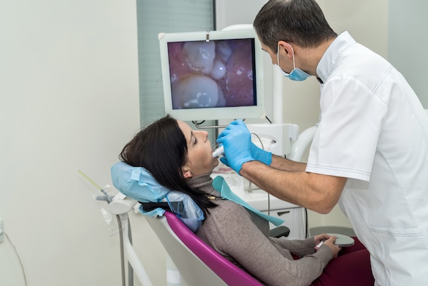 Dentista che controlla i denti del paziente con la macchina fotografica in stomatologia