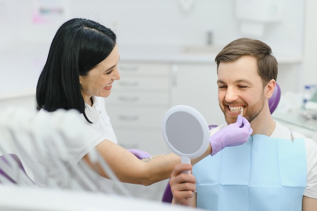 Dentist checking and selecting color of young man's teeth