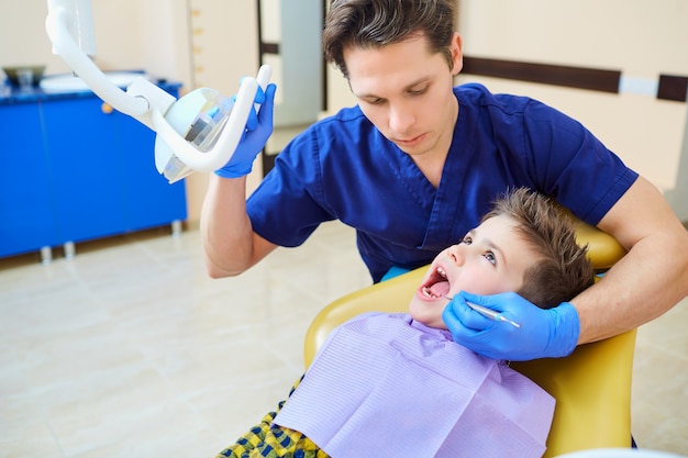 Il dentista che controlla i denti dell'adolescente del ragazzo nell'ufficio del dentista.