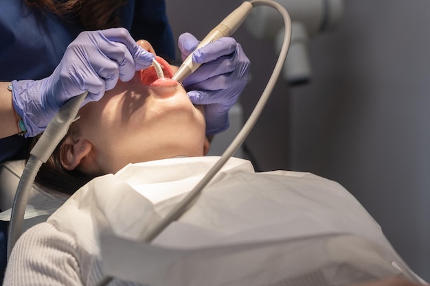 Стоматолог очищает рот пациента