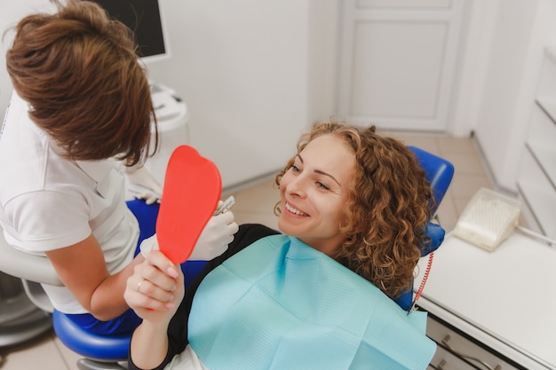 The dentist comparing patient's teeth shade with samples for bleaching treatment