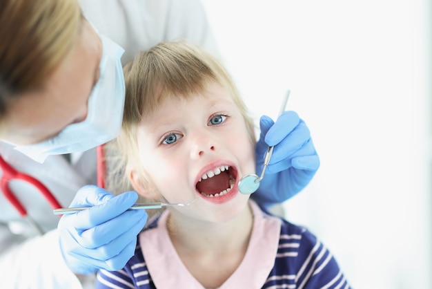 치과 의사가 어린 소녀의 치아 건강 진단을 실시합니다.