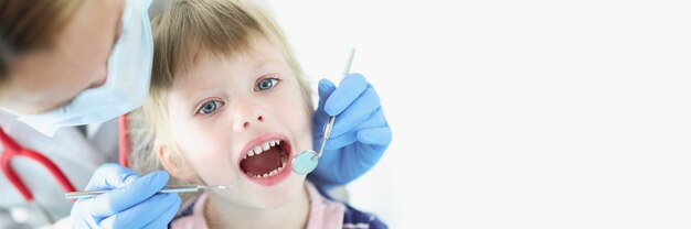 Dentist conducts medical examination of teeth of little girl