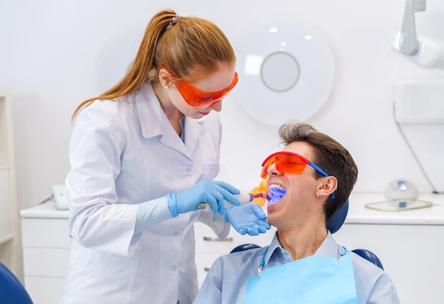 Dentist curing teeth of patient with light