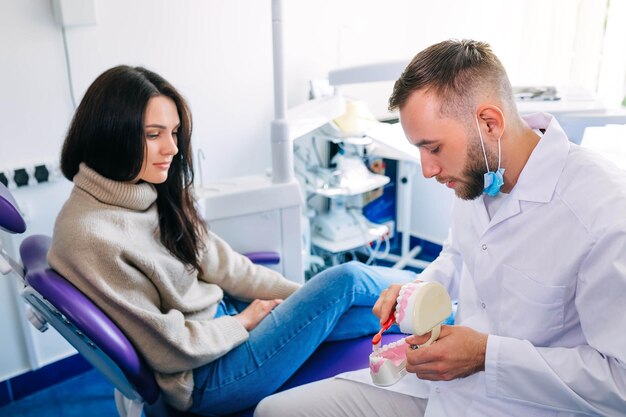 Foto dentista dimostrare come lavarsi i denti correttamente al paziente