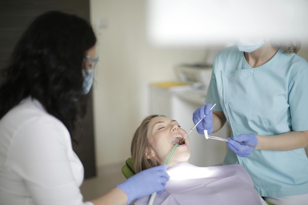 Photo dentist in dental office talking with female patient and preparing for treatment